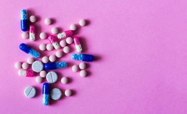 Pembe arka planda yığınla hap, tablet, kapsül. Fotokopi alanı arka planında tedavi için ilaç reçetesi