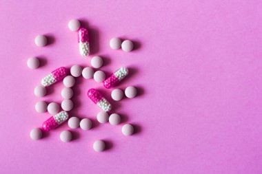 Pembe arka planda yığınla hap, tablet, kapsül. Fotokopi alanı arka planında tedavi için ilaç reçetesi
