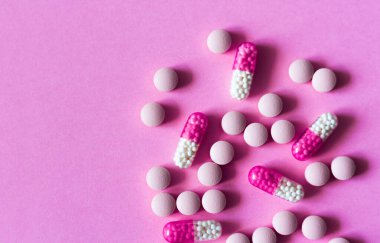 Pembe arka planda yığınla hap, tablet, kapsül. Fotokopi alanı arka planında tedavi için ilaç reçetesi