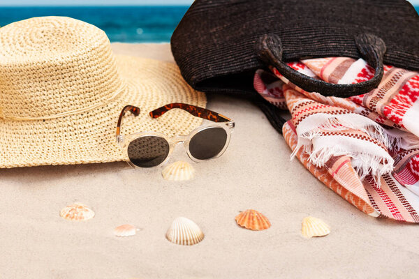 Винтажная летняя плетеная соломенная пляжная сумка, шляпа, парео и солнцезащитные очки на берегу Катании, Сицилия, Италия
