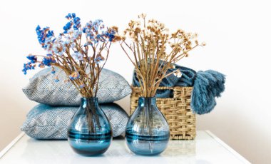 Konforlu ev dekorasyonu: yastık, ekose, odadaki beyaz rafta çiçekli mavi vazo. Karantina konsepti: