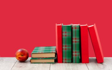 Okula geri döndüm, renkli örtüler içinde bir yığın kitap ve boş pembe arka planlı ahşap masada kırmızı şeftali. Uzaktan eğitim. Karantina konsepti: