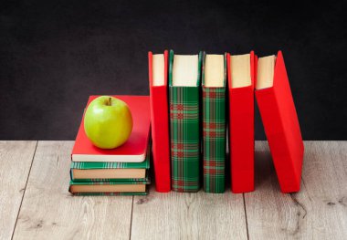 Okula geri döndüm, renkli kapaklar içinde bir yığın kitap ve boş siyah okul geçmişi olan ahşap masa üzerinde yeşil elma. Uzaktan eğitim. Karantina konsepti:
