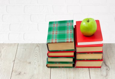 Okula geri döndüm, renkli örtüler içinde bir yığın kitap ve beyaz arka planlı ahşap masada yeşil elma. Uzaktan eğitim. Karantina konsepti: