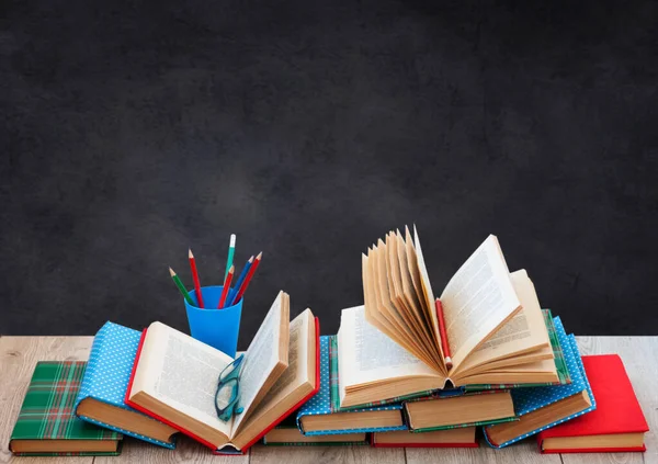 Back to school, pile of books in colorful covers and on wooden table with empty black school board background. Distance home education.Quarantine concept of stay home