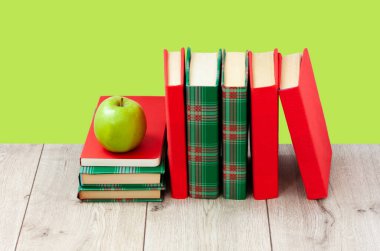 Okula geri döndüm, renkli örtüler içinde bir yığın kitap ve yeşil nane yeşili arkaplanlı ahşap masa üzerinde yeşil elma. Uzaktan eğitim. Karantina konsepti:
