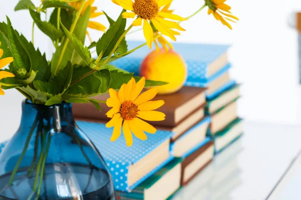 Konforlu ev dekorasyonu: Masasında sarı çiçekler olan bir yığın kitap ve vazo. Uzak ev eğitimi. Evde kalma karantina kavramı.