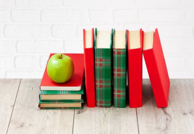 Okula geri döndüm, renkli örtüler içinde bir yığın kitap ve beyaz arka planlı ahşap masada yeşil elma. Uzaktan eğitim. Karantina konsepti: