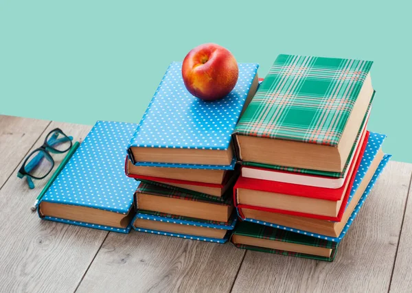 Back to school, pile of books in colorful covers and peach on wooden table with green mint background. Distance home education.Quarantine concept of stay home.