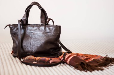 Gri koltukta kadın kahverengi deri çanta, kadın aksesuar.