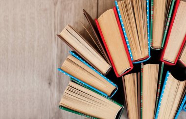 Kitaplar ahşap bir arka planda renkli kapaklar halinde. Okul mesafesindeki ev eğitimine geri dönüyoruz. Evde kalma karantina kavramı.