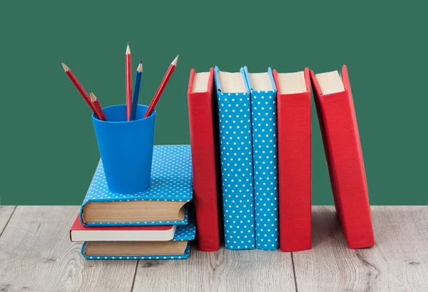 Yeşil arka planda renkli kapaklar içeren ders kitapları. Okul mesafesindeki ev eğitimine geri dönüyoruz. Evde kalma karantina kavramı.