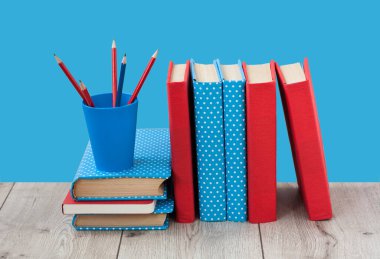 Kitaplar mavi arka planda renkli kapaklar halinde. Okul mesafesindeki ev eğitimine geri dönüyoruz. Evde kalma karantina kavramı.