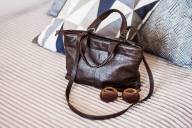 Gri koltukta kadın kahverengi deri çanta, kadın aksesuar.