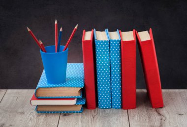 Renkli kapaklarda kitap yığını ve tahta masa üzerinde tahta arka planda kalem. Uzaktan eğitim. Okula dönmek, karantina konsepti evde kalmak.