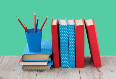 Yeşil arka planda renkli kapaklar içeren ders kitapları. Okul mesafesindeki ev eğitimine geri dönüyoruz. Evde kalma karantina kavramı.