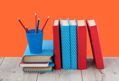 Kitaplar turuncu kırmızı arka planda renkli kapaklar halinde. Okul mesafesindeki ev eğitimine geri dönüyoruz. Evde kalma karantina kavramı.