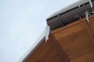 Çatıdaki buz saçakları siyah bir arka planda. Çatıdan sarkan buz saçakları.