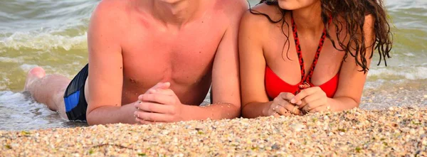 Genç adam ve kız denizde bir fotoğrafçıya poz veriyorlar.