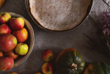 Hazırlık, Şükran Günü kutlaması. Kavram. Turta hamurlu tavanın üst görüntüsü, gri keten masa örtüsü üzerinde elma ve balkabağı vazosu..