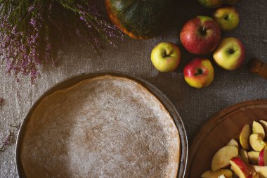 Hazırlık, Şükran Günü kutlaması. Kavram. Turta hamurlu tavanın üst görüntüsü, gri keten masa örtüsü üzerinde elma ve balkabağı vazosu..