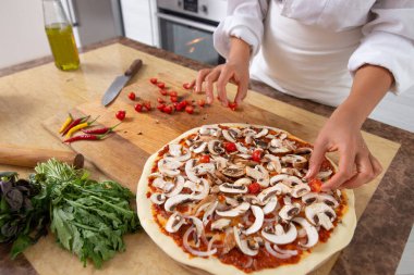 Şefin, pizza malzemelerine domates eklediği yakın plan çekimler. Vejetaryen yemeği.