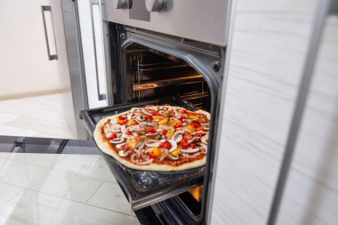 Fırındaki fırın tepsisindeki çiğ pizza. Vejetaryen yemeği.