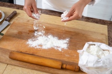 Ahşap tahtaya un serpiştiren şefin ellerine yakın plan..