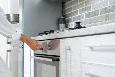 Genç kadın aşçı fırını yemek pişirmek için ayarlar. Yakın plan..