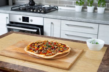 Yuvarlak ahşap bir tahtanın üzerinde pişmiş pizzanın manzarası. Vejetaryen yemeği.