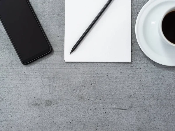 スマートフォンを望むオフィススペースのフラットレイアウト 鉛筆とコーヒーのカップ付きのメモ帳 — ストック写真