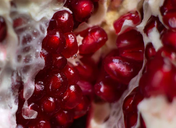 Close-up of the inner contents of the cut pomegranate. Close-up of pomegranate seeds are visible. Background.