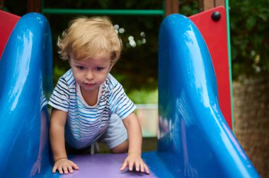 Genç bir çocuk, canlı bir oyun parkı kaydırağında macera ve keşiflerle dolu bir günün tadını çıkarıyor. Sahne, gençliğin neşe ve merakını çekici ve renkli bir ortamda yakalıyor..