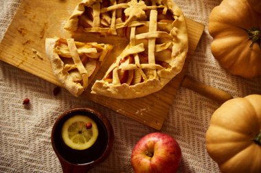 Kırsal sonbahar masasında kafes üstü turta, balkabağı, elma ve limon dilimli bir kupa var. Sıcak, hasat havası Şükran Günü, sonbahar tarifleri ve mevsimlik kutlamalar için ideal..