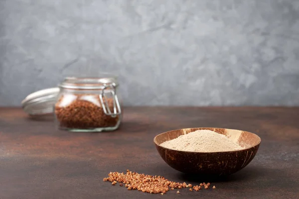 buckwheat flour in a bowl, buckwheat on the concrete background. copy space