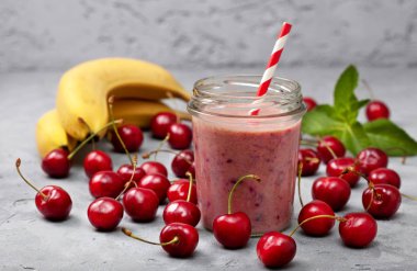kiraz Muz smoothies bir cam kavanoz, taze kiraz ve gri beton zemin üzerine muz