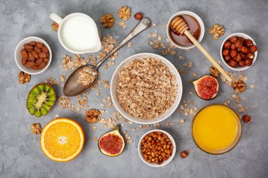 Sağlıklı kahvaltı: müsli ve taze meyveler: portakal, incir, kivi ve fındık üzerinde gri bir arka plan beton. yukarıdan görüntülemek