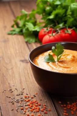 Kahverengi bir kase, taze domates, maydanoz bir eski ahşap arka plan üzerinde kırmızı mercimek çorbası püresi. kopya alanı