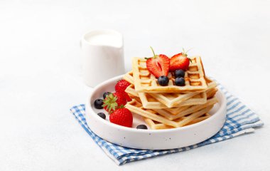 Sağlıklı kahvaltı. Taze çilek ile Belçika Waffle: yaban mersini ve çilek, nane hafif bir arka plan üzerinde