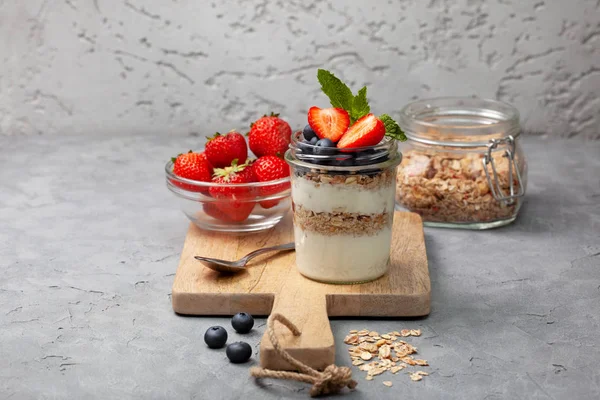 sağlıklı diyet kahvaltı. granola, yoğurt, yaban mersini, çilek gri beton zemin üzerine bir kavanoza. kopya alanı