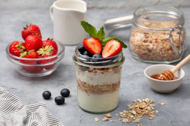 sağlıklı diyet kahvaltı. granola, yoğurt, yaban mersini, çilek gri beton zemin üzerine bir kavanoza. kopya alanı