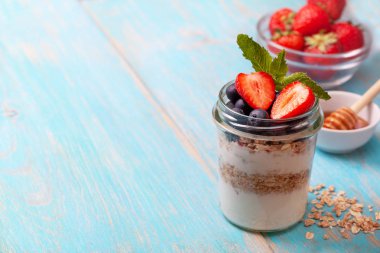 sağlıklı diyet kahvaltı. granola, yoğurt, yaban mersini, çilek mavi ahşap arka plan üzerinde bir kavanoza. kopya alanı