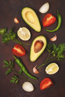 Guacamole için malzemeler: avokado, limon, domates, soğan ve baharat kahverengi bir arka plan üzerinde. yukarıdan görüntülemek. 