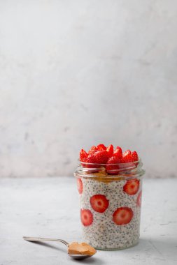sağlıklı kahvaltı. çilek, gri bir arka plan üzerinde bir cam kavanoza chia tohum ile gece yulaf ezmesi