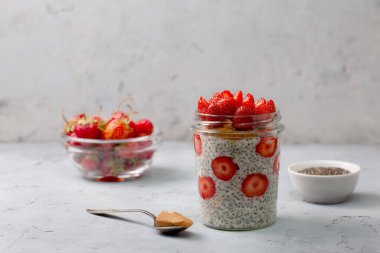 sağlıklı kahvaltı. çilek, gri bir arka plan üzerinde bir cam kavanoza chia tohum ile gece yulaf ezmesi