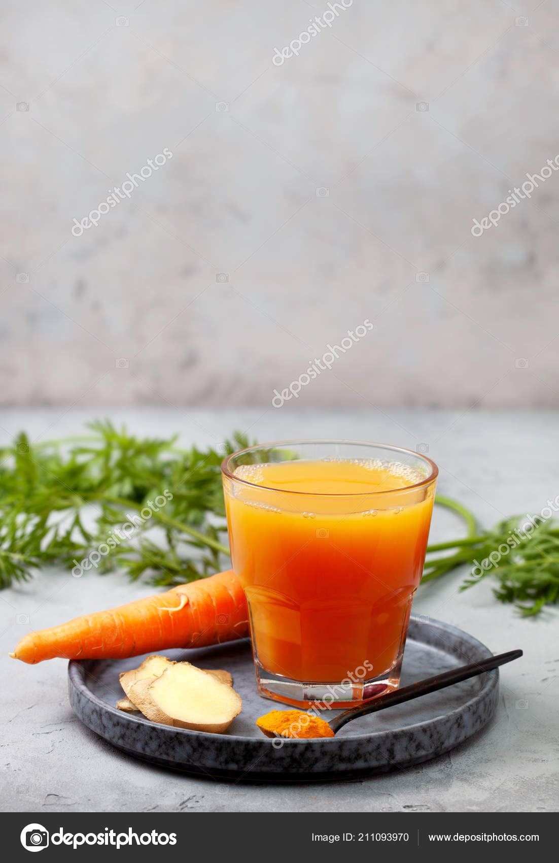 Fresh detox carrot juice in glass bottles on a gray stone