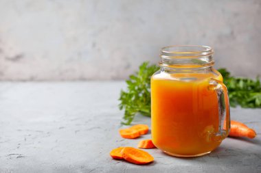 havuç suyu cam kavanozda, arka planı gri taş yakın çekim üzerinde taze havuç