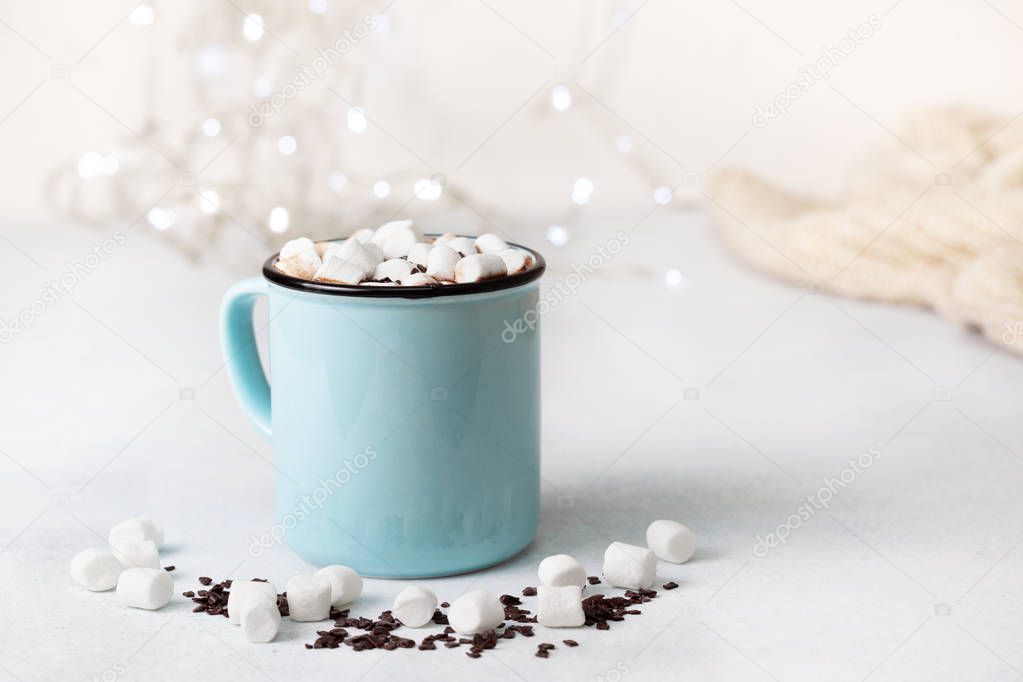 hot chocolate with marshmallow in a blue mug on a gray stone background