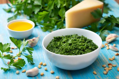 pesto maydanoz yemek pişirmek için malzemeler. taze maydanoz, zeytinyağı, parmesan peyniri, çam fıstığı ahşap mavi arka plan üzerinde