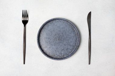 boş tabak, çatal, kaşık ve bıçak gri beton zemin üzerine. yukarıdan görüntülemek